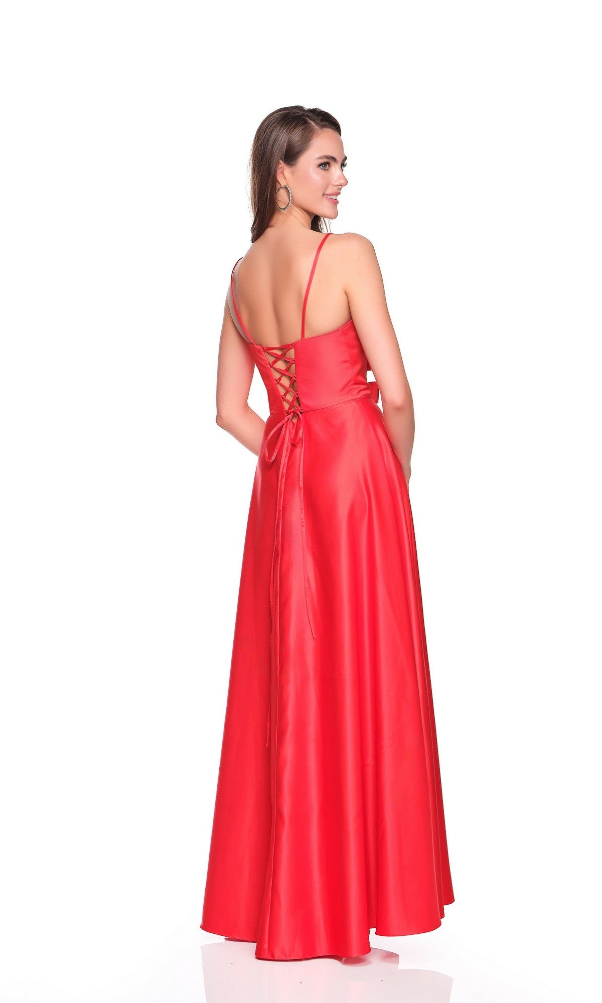 A woman models the Dave and Johnny 12572 long prom dress in striking red, featuring a lace-up back, as she stands and looks over her shoulder against a white background.